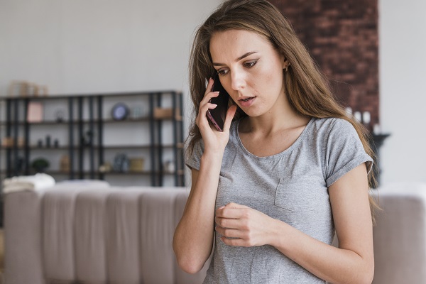 femeie tanara, ingrijorata, vorbind la telefon