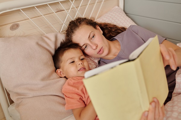 mama care se uita pe o carte cu baietelul ei inainte de culcare