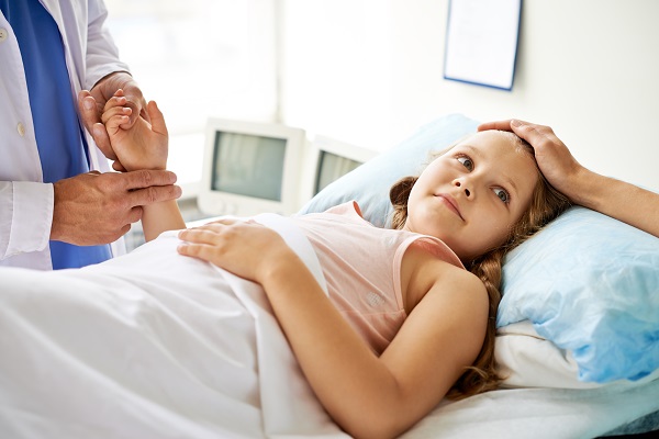 medic care verifica pulsul unei fetite care sta in pat la spital