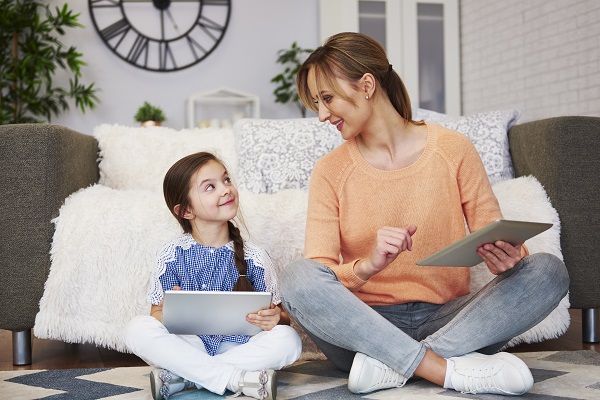 mama si fetita care stau pe jos si lucreaza amandoua cu tableta