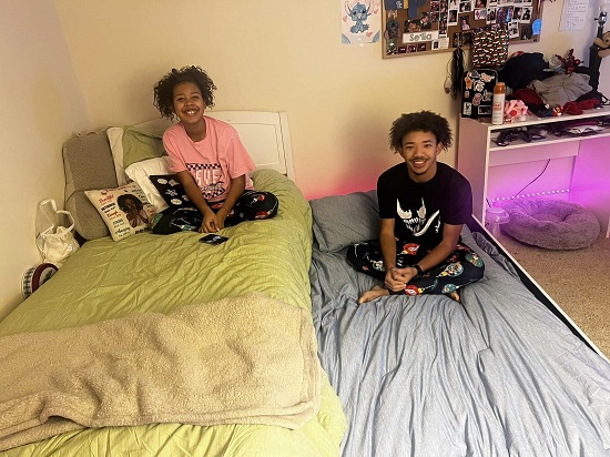 doi adolescenti fericiti, stand fiecare pe un pat intr-un dormitor