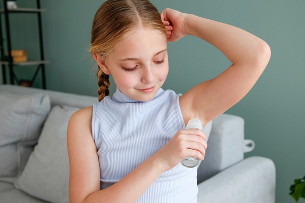 adolescenta care sta pe canapea si utilizeaza un antiperspirant roll-on