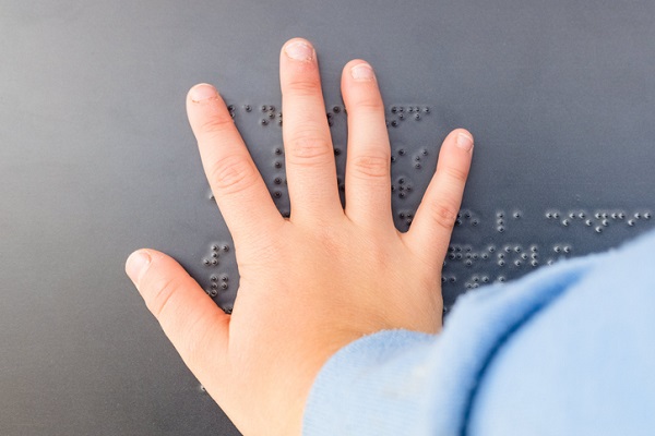 mana de copil care incearca sa descifreze un text scris in alfabetul Braille