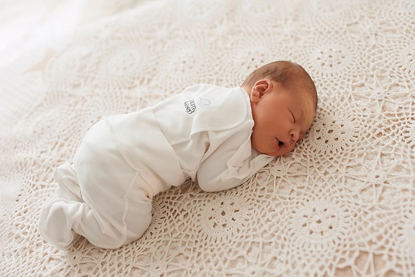 bebelus care doarme pe burtica, in pantalonasi albi