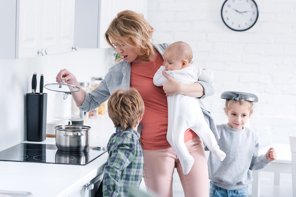 mama cu copiii in bucatarie in timp ce incearca sa gateasca