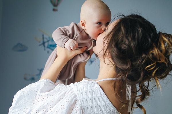 mama entuziasmata care isi tine bebelusul ce o pupa in brate