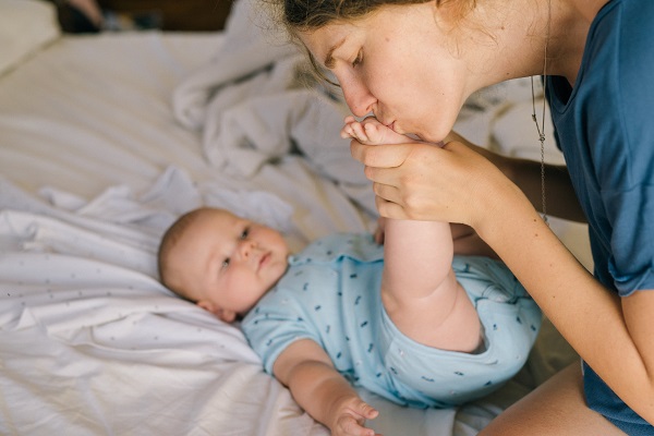 mama care saruta piciorusul bebelusului ei