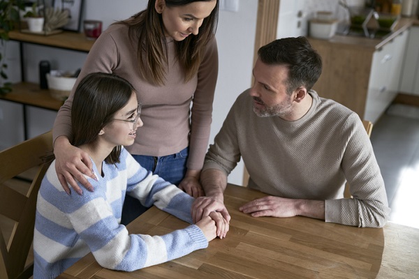 parinti zambitori si afectuoasi care discuta, la masa, cu fiica lor adolescenta