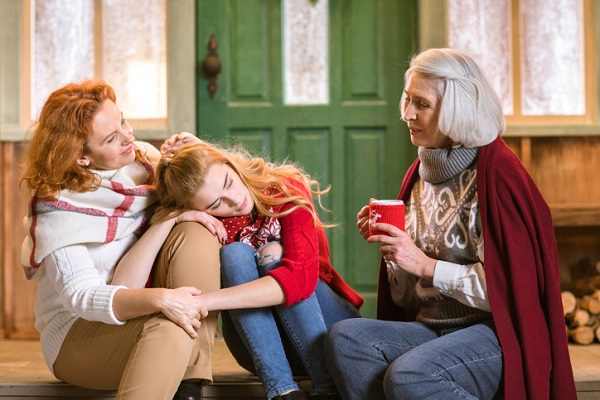 mama care isi alina fiica adolescenta in timp ce o femeie in varsta sta langa ele si le sfatuieste