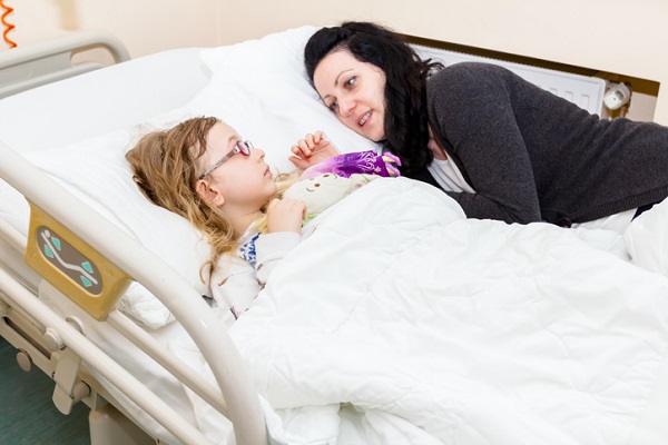 mama care sta intinsa pe patul de spital alaturi de fetita ei bolnava