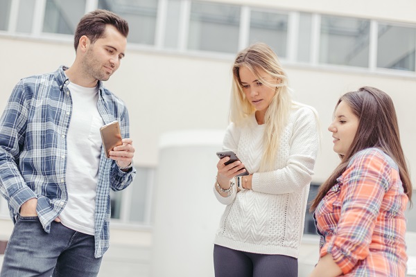 femeie care vrea sa le arate ceva pe telefon altor adulti din preajma ei