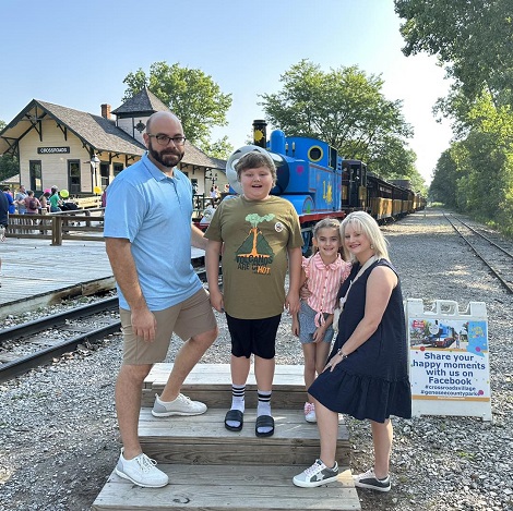 mama, tata si cei doi copii ai lor veseli vizitand o gara in care se afla trenuletul Thomas