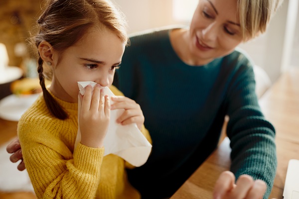 mama care sta langa fetita ei care isi sufla nasul