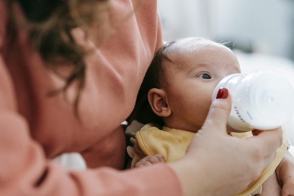 mama care isi hraneste bebelusul cu biberonul