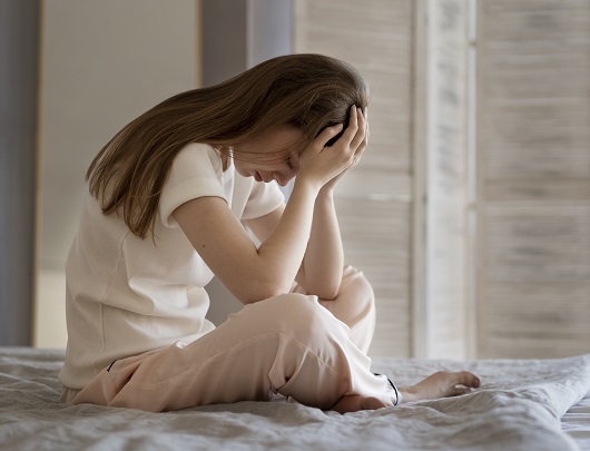 femeie tanara, deprimata, stand pe pat in pijama