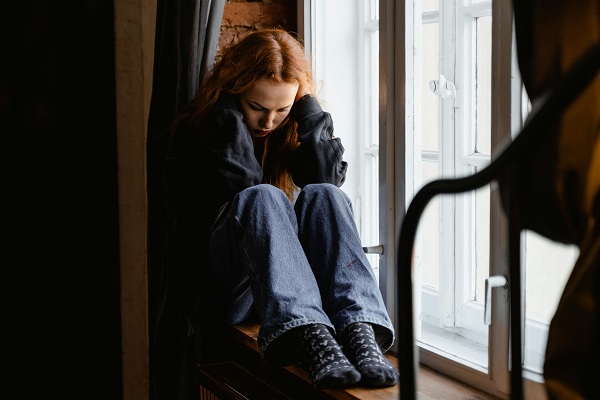 femeie deprimata stand pe pervazul ferestrei