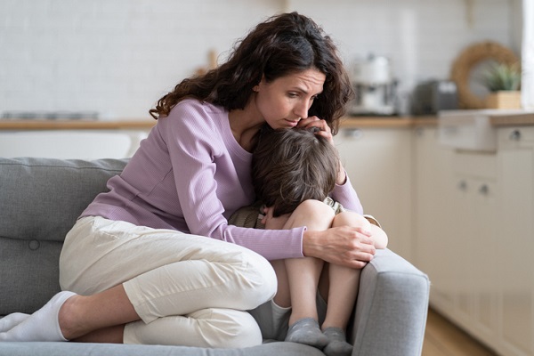 mama care sta pe canapea si isi strange in brate baietelul deprimat sau speriat