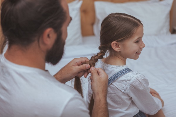 barbat care îi face o codita impletita unei fetite