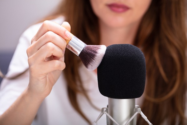 femeie care atinge cu o pensula un microfon pentru a produce o experienta asmr