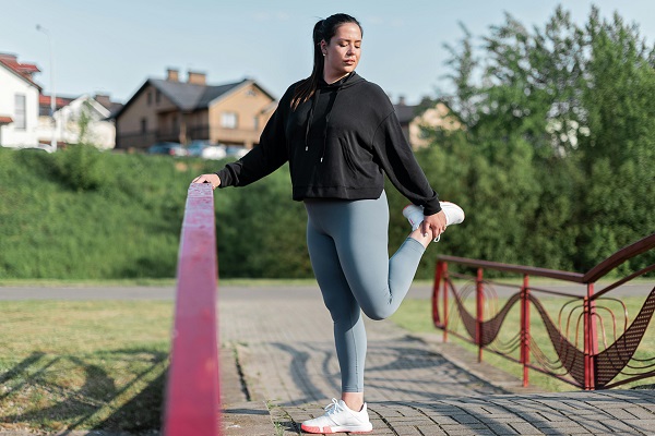 femeie tanara imbracata in tinuta sport in timp ce face un exercitiu tip stretching 