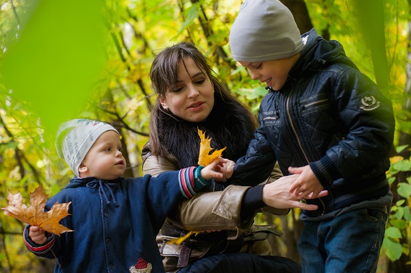 mama si fiii ei adunand frunze de toamna