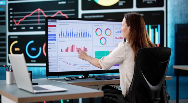 femeie care sta in fata computerului ca sa analizeze grafice speciale dintr-o aplicatie software pentru finante