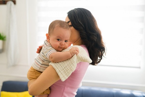 mama care isi tine bebelusul in brate in pozitie verticala ca sa-l ajute sa eructeze