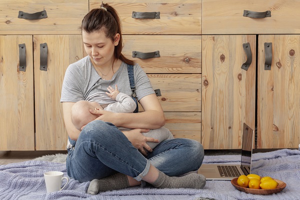 mama care isi alapteaza bebelusul in timp ce sta pe podea