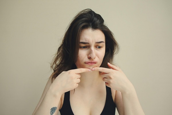 femeie tanara trista, care isi atinge un coș de pe față