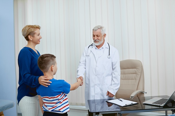baietel însoțit de mama lui dând mâna cu doctorul său