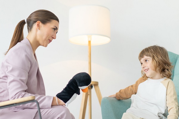 terapeut care face un joc de rol cu un baietel in timpul unei ședințe de terapie