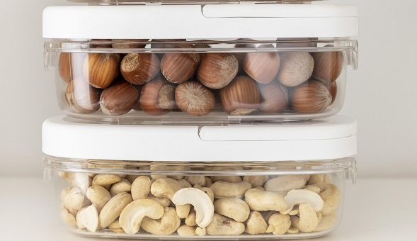 alune de padure si nuci caju depozitate in caserole de plastic transparente cu capace albe