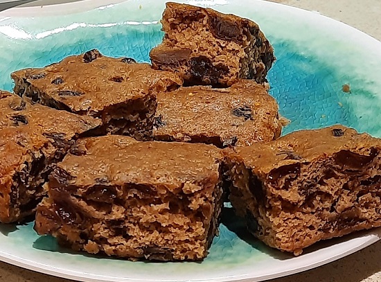 bucati de turta dulce pufoasa, cu fructe in interior, puse pe o farfurie bleu cu alb