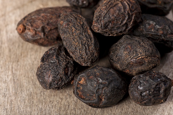 fructe uscate ale arborelui Serenoa repens sau palmier pitic, asezate pe o suprafata de lemn maro deschis