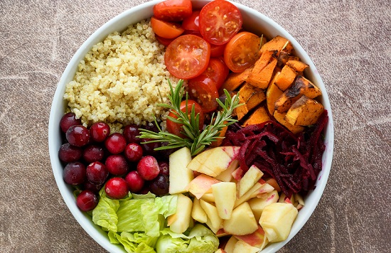 castron alb in care se afla alimente sanatoase, quinoa si diverse legume, in mijlocul castronului fiind pusa o crenguta de rozmarin proaspat