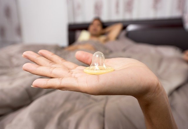 cuplu-in-dormitor-prezervativ-in-palma