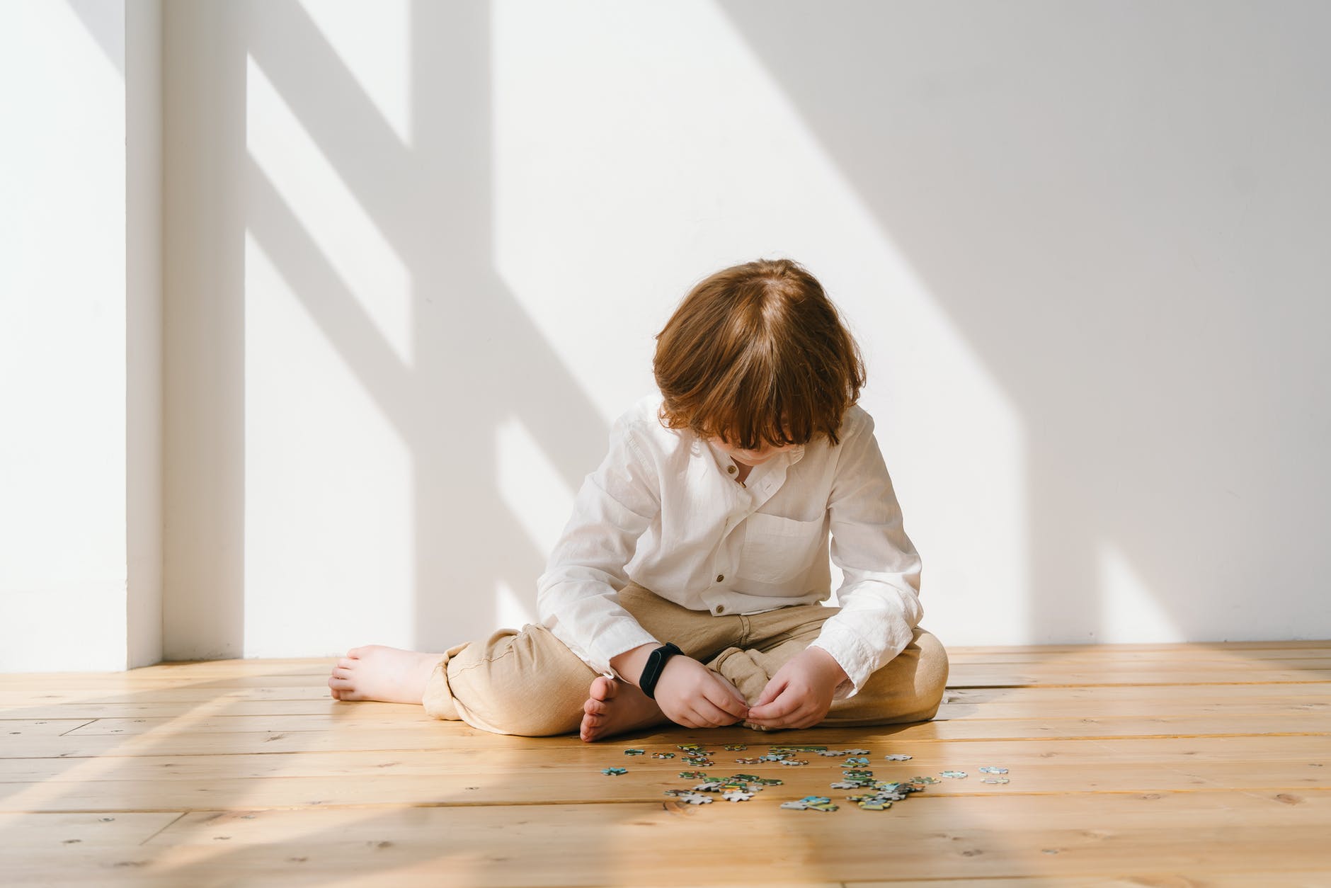 copil care face un puzzle pe podea
