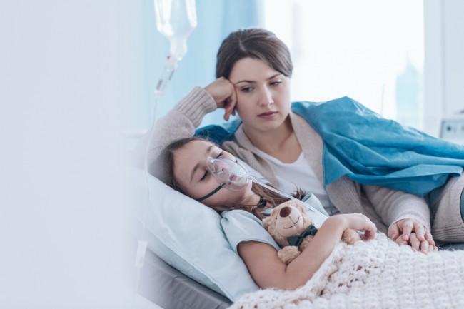 femeie care sta langa fetita pe patul de spital