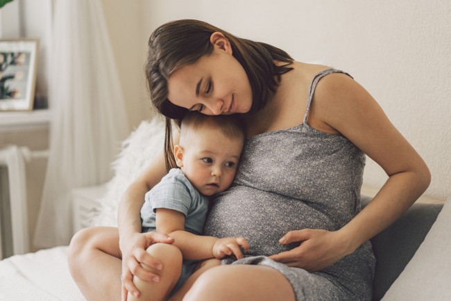 femeie insarcinata care isi imbratiseaza copilul