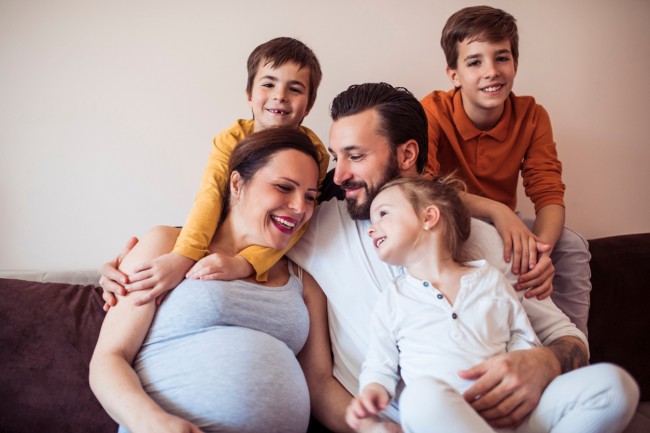 femeie insarcinata care sta pe canapea cu familia ei