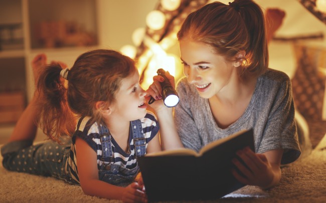 mama cu copilul citind povesti cu lanterna