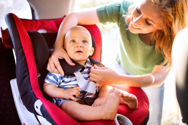 mama care fixeaza copilul in scaunul auto