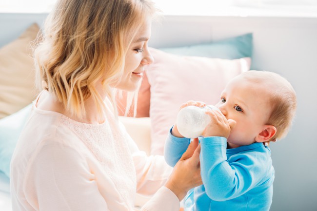 mama care isi hraneste bebelusul cu biberonul