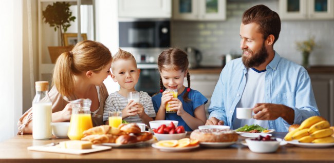 familie cu doi copii care mananca impreuna micul dejun