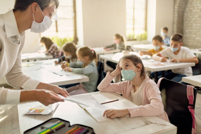 Eleva cu masca care discuta cu profesoara