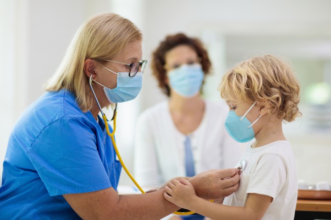copil care poarta masca si este consultat de medic cu stetoscopul