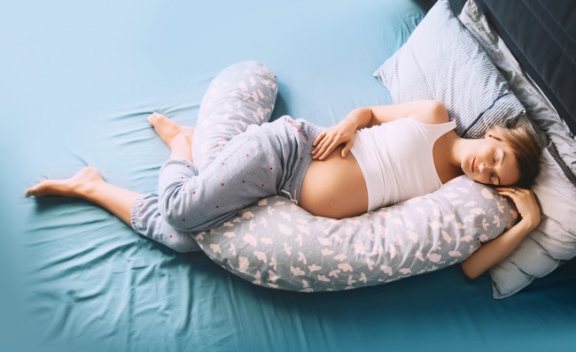 femeie insarcinata care doarme pe o perna de gravide