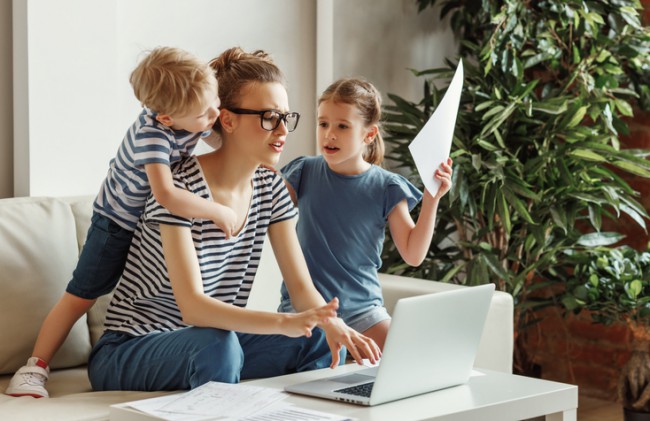 mama care lucreaz ala laptop si doi copii in jurul ei