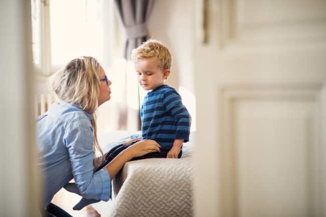 mama care vorbeste cu copilul care sta pe pat