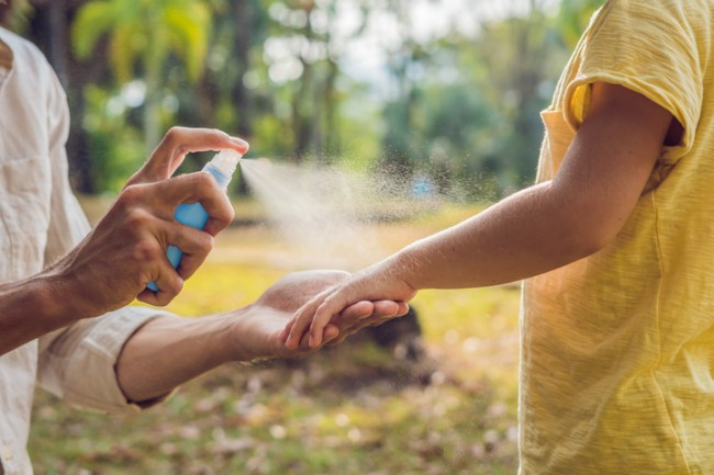 mama care aplica un spray repelent pe bratul unui copil